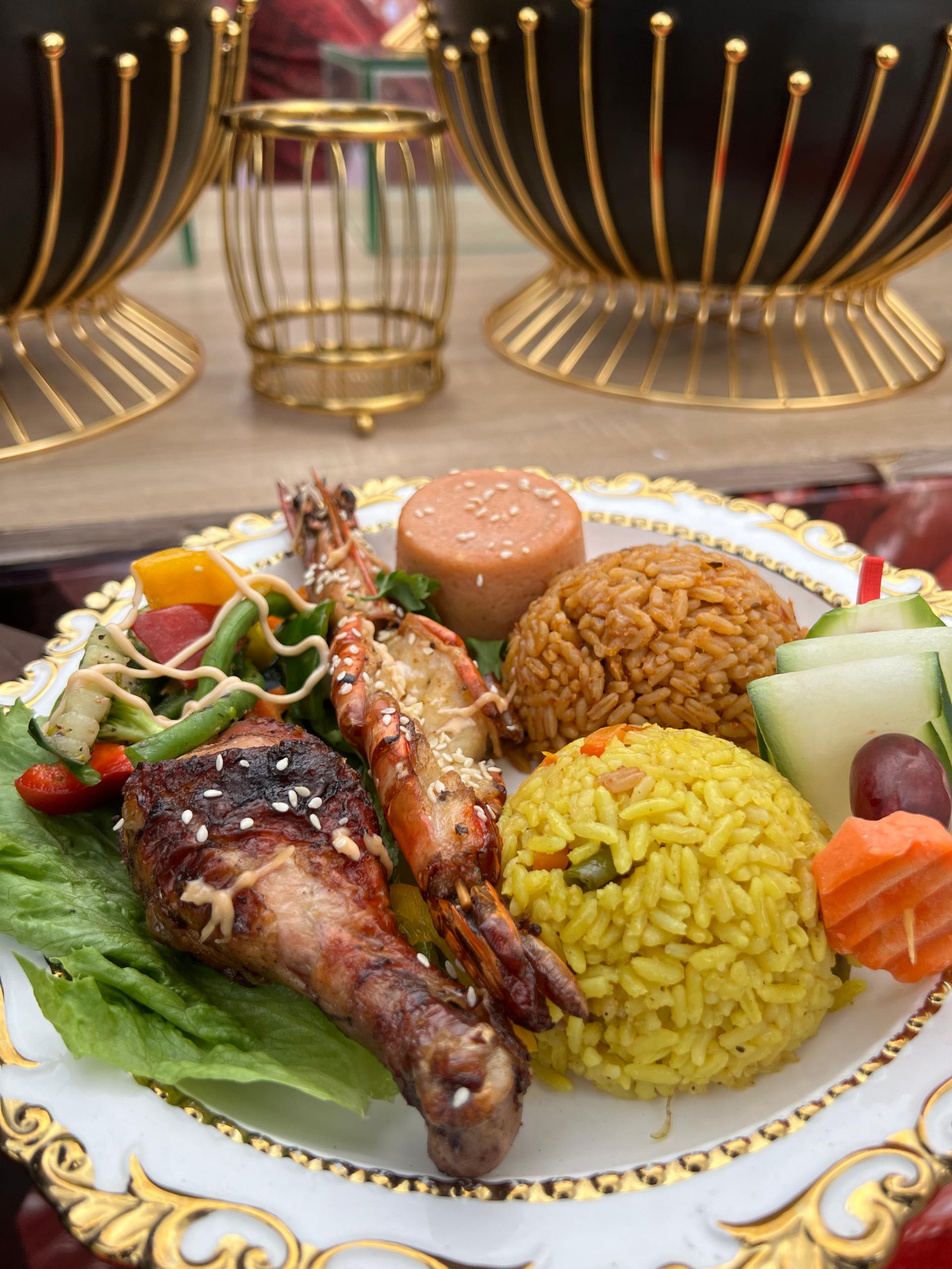 Smokey Jollof Rice, Signature Fried Rice,Special Vegies, Salad, Moinmoin with Peppered Chicken and Prawn
